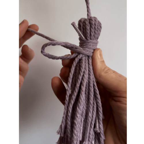 Craftsman handmaking tassels for use in garments, accessories, and traditional textile products.